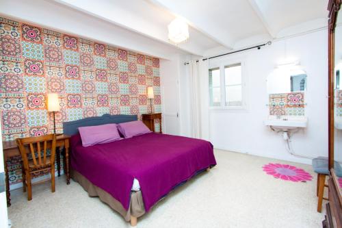 蒙彼利埃Montpellier Boutonnet avec jardin的一间卧室配有一张紫色的床和一张书桌