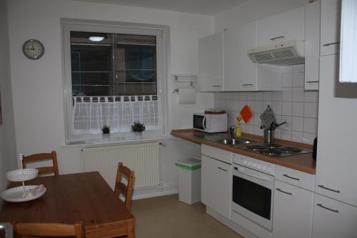 吕贝克Andrea的厨房配有白色橱柜、桌子和窗户。