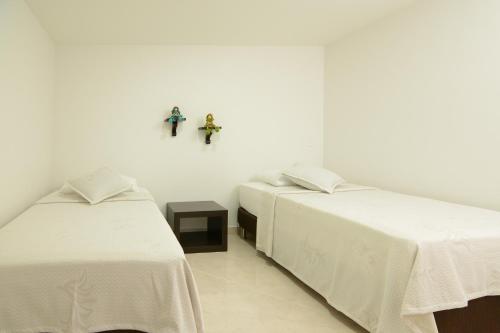 恩维加多Acogedor Apartamento 2 Habitaciones S31的白色客房的两张床,墙上有十字架