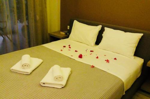 普拉基亚斯New Luxury Apartments in Plakias的一张带白色毛巾和红色鲜花的床