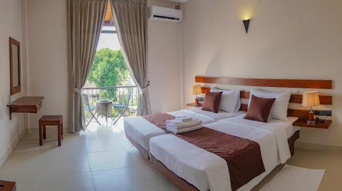 尼甘布Hive 68 - Hotel and Resorts (Negombo)的一间带大床的卧室和一个阳台