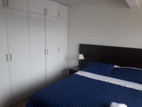 利马Departamento en Chacarilla, San Borja的一间卧室配有蓝色的床和白色橱柜