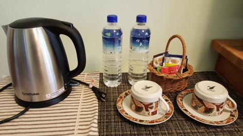 Fengli艺田民宿 的茶壶和桌子上的两个杯子及水瓶