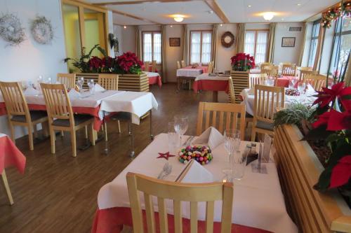 GuggisbergHotel Restaurant Sternen的餐厅设有桌椅,并配以红色的鲜花