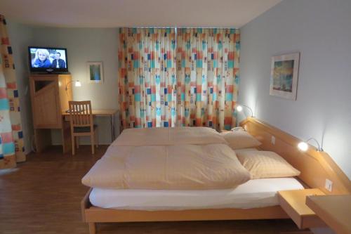 GuggisbergHotel Restaurant Sternen的一间卧室配有一张床和一台电视。