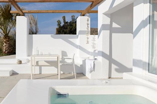 图罗斯Amare Mykonos的白色的房子,配有桌椅和游泳池