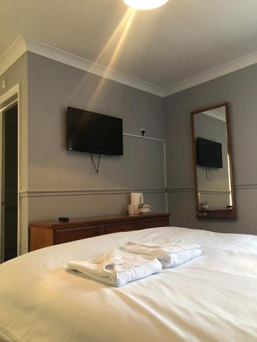 赖德The Crown Hotel的卧室配有一张白色床,墙上配有电视