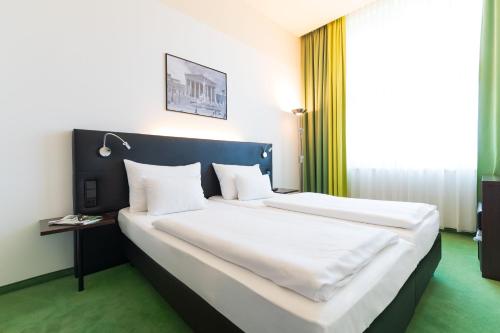 维也纳维也纳雷纳斯酒店的卧室配有一张带白色床单和枕头的大床。