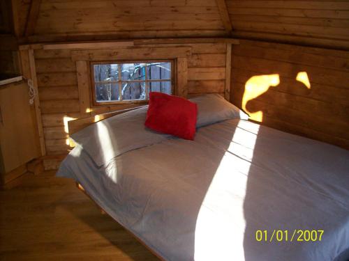 威廉堡The Hobbit House的小木屋内的一张床位,上面有红色枕头