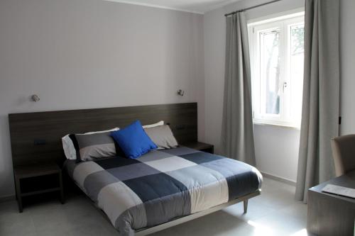 弗罗西诺内EasyRoom Frosinone - Casello Autostradale的一间卧室配有一张带蓝色枕头的床和一扇窗户。
