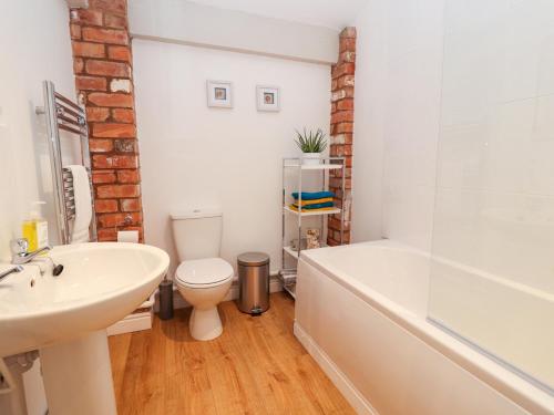 雷克瑟姆Commonwood Cottage的浴室配有盥洗盆、卫生间和浴缸。