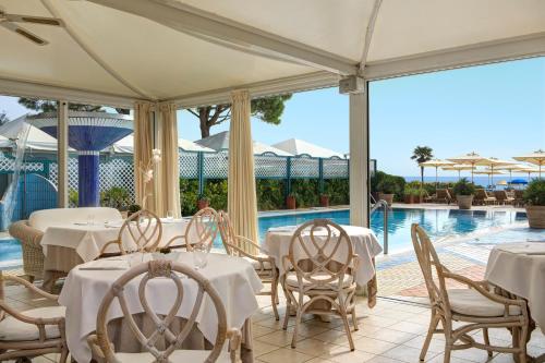利多迪耶索罗拉西利亚帕克酒店的一间带白色桌椅的餐厅和一个游泳池