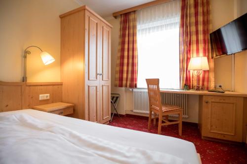 穆勒克Wirtshaus Restaurant Pension Steirerland的配有一张床、一张书桌和一扇窗户的酒店客房