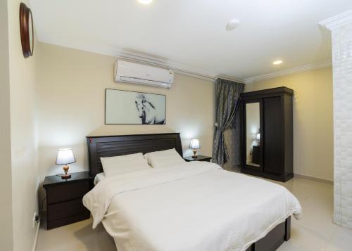 阿可贺巴Eastren Front的卧室配有一张白色大床和两盏灯。