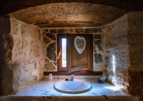 CamasobresHotel Posada Fuentes Carrionas的石质浴室设有水槽和窗户
