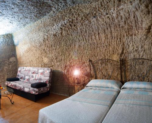 贝赫尔-德拉弗龙特拉Hostal Batato的一间卧室设有两张床、一张沙发和一堵墙