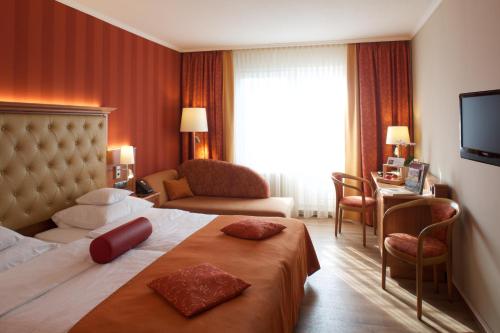 Oranienbaum-Wörlitz祖姆斯汀环形酒店的酒店客房配有床、沙发和电视。