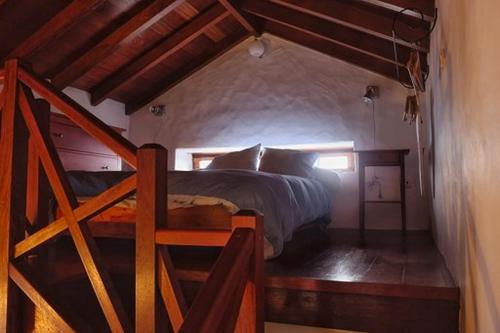 GuarazocaCasa Rural El Tenique的一间卧室设有一张床和木制楼梯。