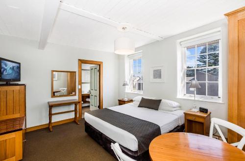仙女港Seacombe House Motor Inn Port Fairy的一间卧室配有一张床、一张桌子和一台电视