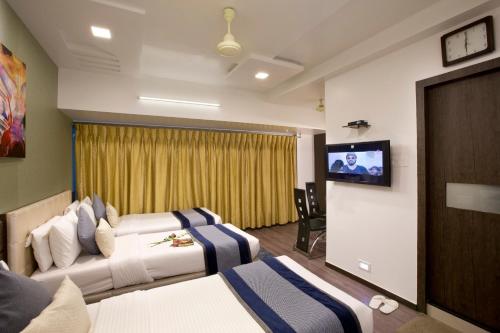 孟买Hotel Planet Residency的酒店客房设有两张床和一台平面电视。