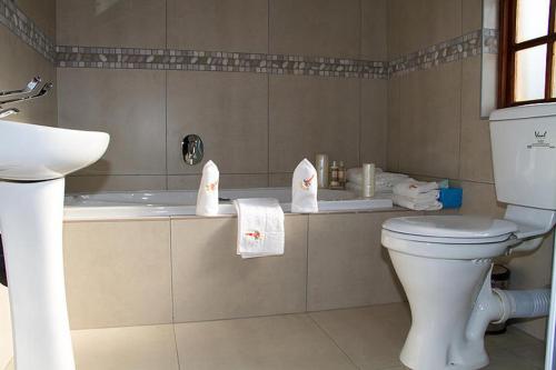 约翰内斯堡Classique Grace Boutique Hotel的浴室配有卫生间、浴缸和毛巾。