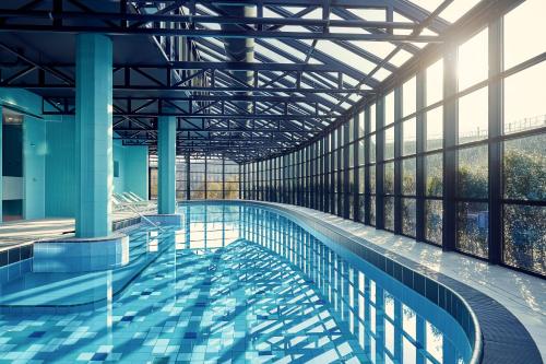 巴德胡弗多普Corendon Urban Amsterdam Schiphol Airport Hotel的一座带大窗户的建筑内的游泳池