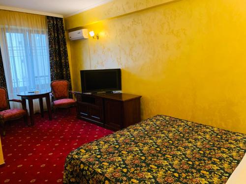 巴克乌Vila Royal的配有一张床和一台平面电视的酒店客房