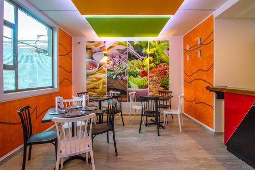 墨西哥城HOTEL ZARAGOZA INN BOUTIQUE的餐厅设有桌椅,墙上挂有绘画作品