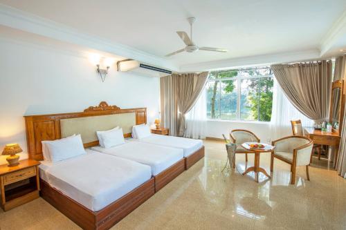 波隆纳鲁沃苏度阿拉利亚酒店的卧室配有一张床和一张桌子及椅子
