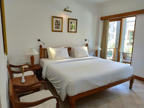 沙努尔普瑞梅沙瑞酒店的卧室设有一张白色大床和一扇窗户。