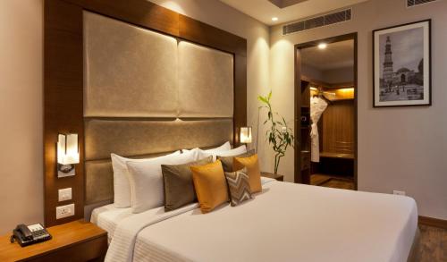 古尔冈Lemon Tree Hotel, Sector 68, Sohna Road, Gurugram的卧室配有一张带黄色枕头的大型白色床。