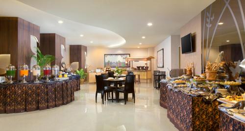 泗水凤蝶贝斯特韦斯特酒店的一间餐厅配有桌椅,提供食物