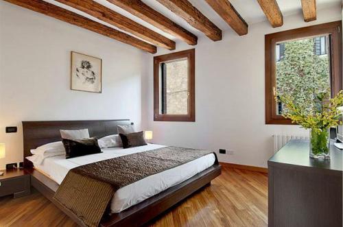 威尼斯Salmaso Apartments的一间卧室设有一张大床和两个窗户。
