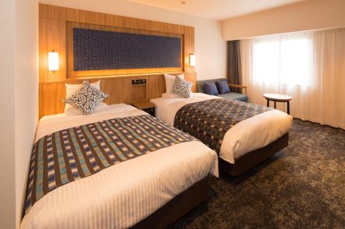 盛冈Art Hotel Morioka的酒店客房,配有两张床和椅子