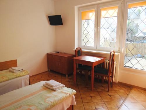华沙Willa Ewa的客房设有两张床、一张桌子和一扇窗户。