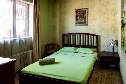 乌兰巴托乌兰巴托莲花民俗的一间卧室配有一张带绿色床单的床和一扇窗户。