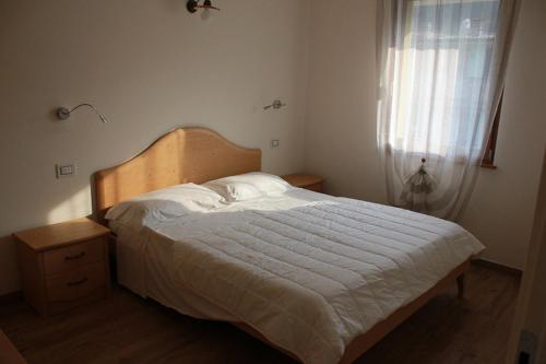 科奥恩Residence Elettra的一间卧室配有一张带白色床罩的床和窗户。