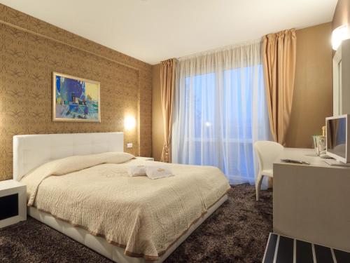 大特尔诺沃阿古斯塔温泉酒店 的一间卧室配有一张床、一张书桌和一个窗户。