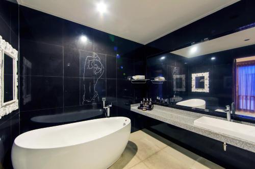 塞米亚克White Lotus Villas Seminyak的浴室配有大型白色浴缸和黑色墙壁