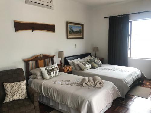 莱迪史密斯Towerzicht Guest House的一间卧室设有两张床、一把椅子和一个窗户。