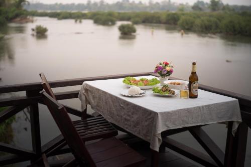 Ban KhonChanhthida Riverside Guesthouse and The River Front Restaurant的一张桌子,上面放着两盘食物和一瓶葡萄酒