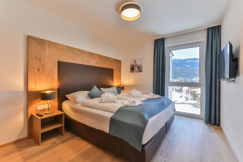 黑马戈尔Lake Resort Pressegger See的一间卧室设有一张大床和大窗户
