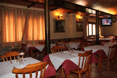 里奥帕尔Venta El Laminador的餐厅设有白色的桌椅和电视。