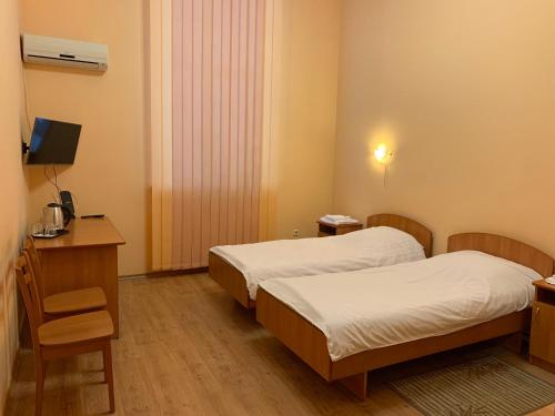 基辅Inn on Zhytomyrska的客房设有两张床、一张桌子和一台电视。