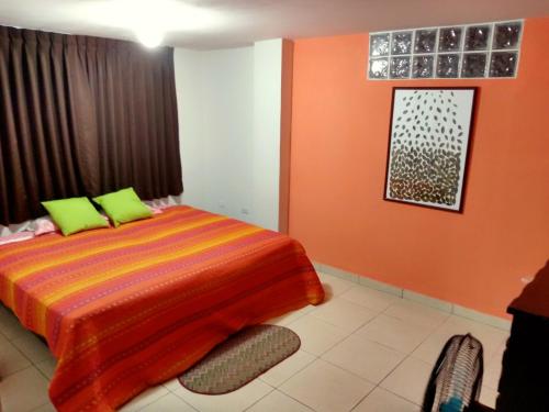 利马La Casa del Che Fernando的一间卧室拥有橙色的墙壁,配有一张带绿色枕头的床。