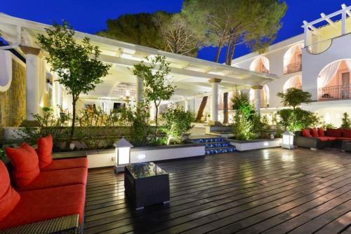 阿西亚罗利La Pineta Hotel Beach & Spa的户外庭院设有红色的沙发和植物