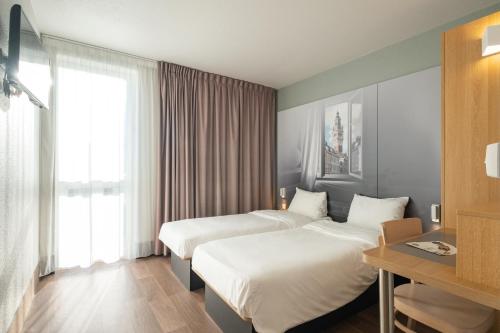 图尔昆B&B HOTEL Lille Tourcoing Centre的酒店客房设有两张床和窗户。