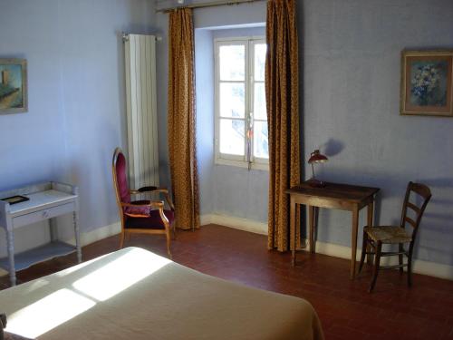 CharlevalLE MAS DU CAPRIER的一间卧室配有一张床、一张书桌和一个窗户。
