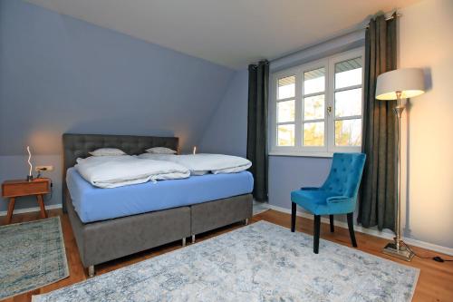 阿伦斯霍普Ferienwohnung im Blauen Haus的一间卧室配有一张床、一把蓝椅和一个窗户。