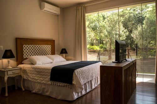 蒂拉登特斯Pousada Recanto das Araras的一间卧室配有一张床、一台电视和一个窗口